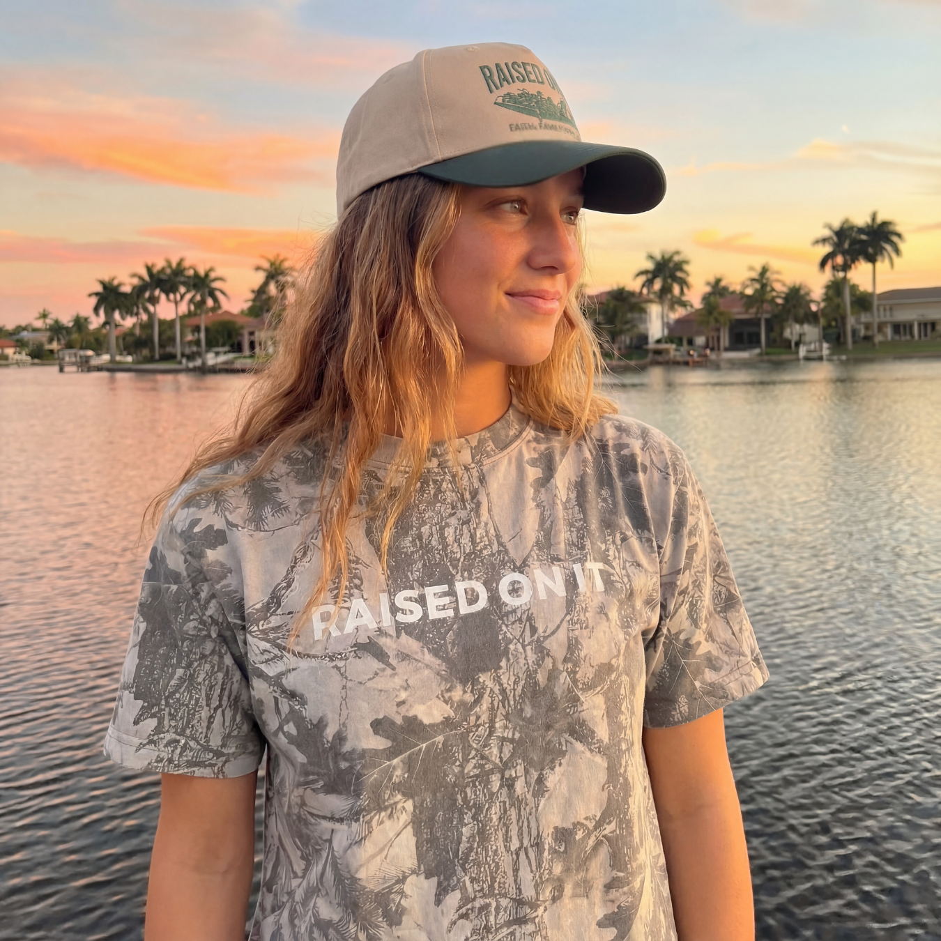Woman wearing the Outboard Legacy Mudboat hat by the water at sunset