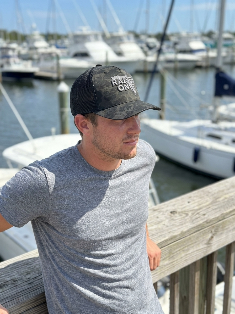 Man wearing the Silver Camo Florida Logo trucker hat leaning on a marina dock railing